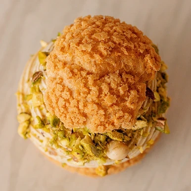 la caprice qui a Pâte à choux, croustillant pistache, cœur framboise, crème légère pistache.